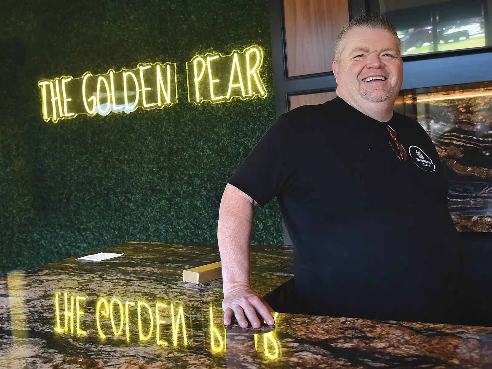Rodney Worth stands in front of the Golden Pear sign